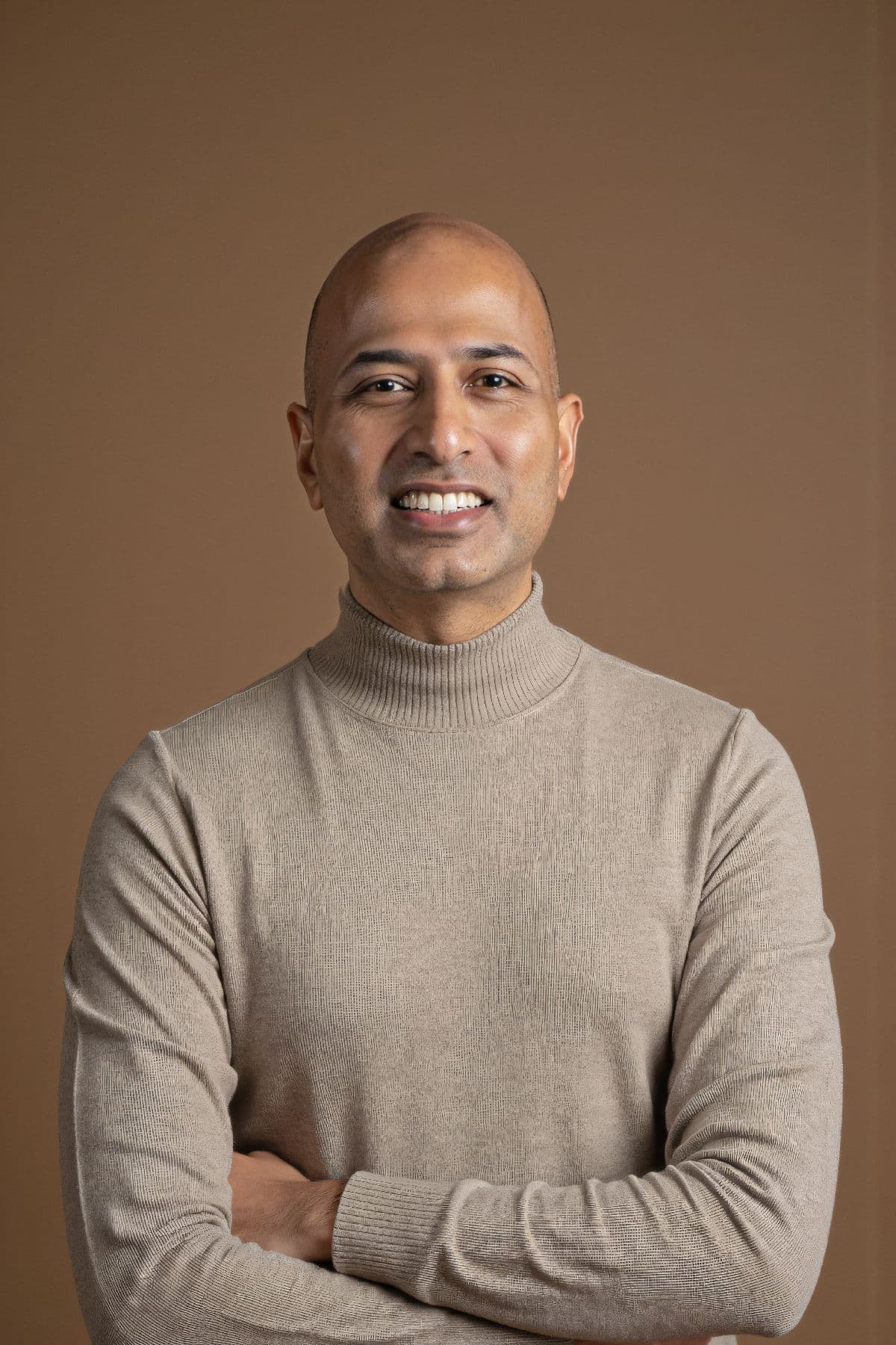 Hari Kiran Chereddi, arms folded, against a clay-brown studio backdrop